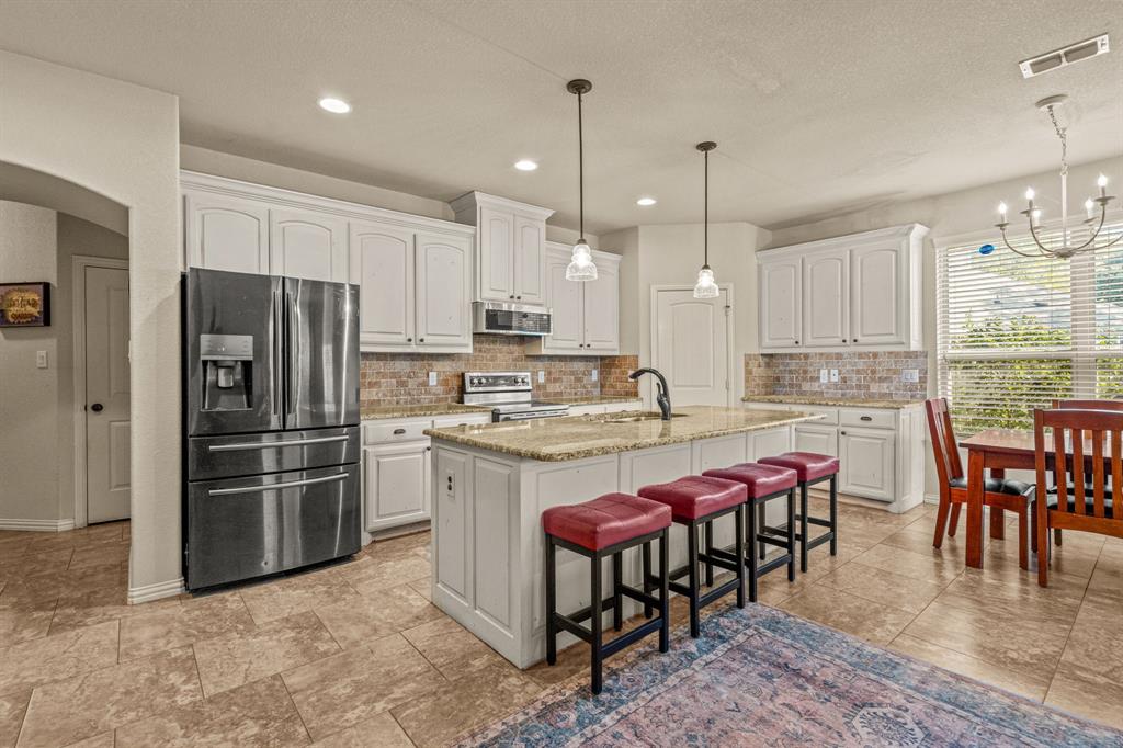 108 Bosque Court Azle, TX 76020 - Photo 7 of 33 a kitchen with kitchen island granite countertop a table chairs microwave and refrigerator