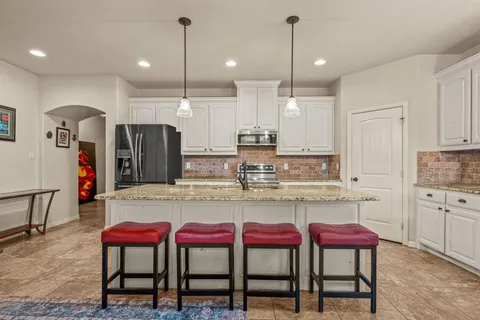 a kitchen with kitchen island a table and chairs in it