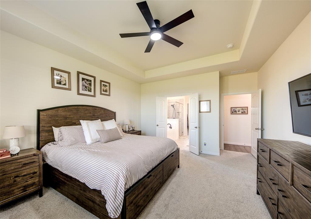 131 Clear Crk Lane Rhome, TX 76078 - Photo 12 of 29 Bedroom featuring a raised ceiling, ensuite bathroom, light carpet, and ceiling fan