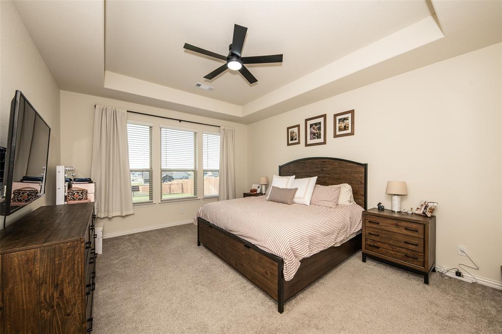 131 Clear Crk Lane Rhome, TX 76078 - Photo 13 of 29 Bedroom featuring light colored carpet, a tray ceiling, and a ceiling fan