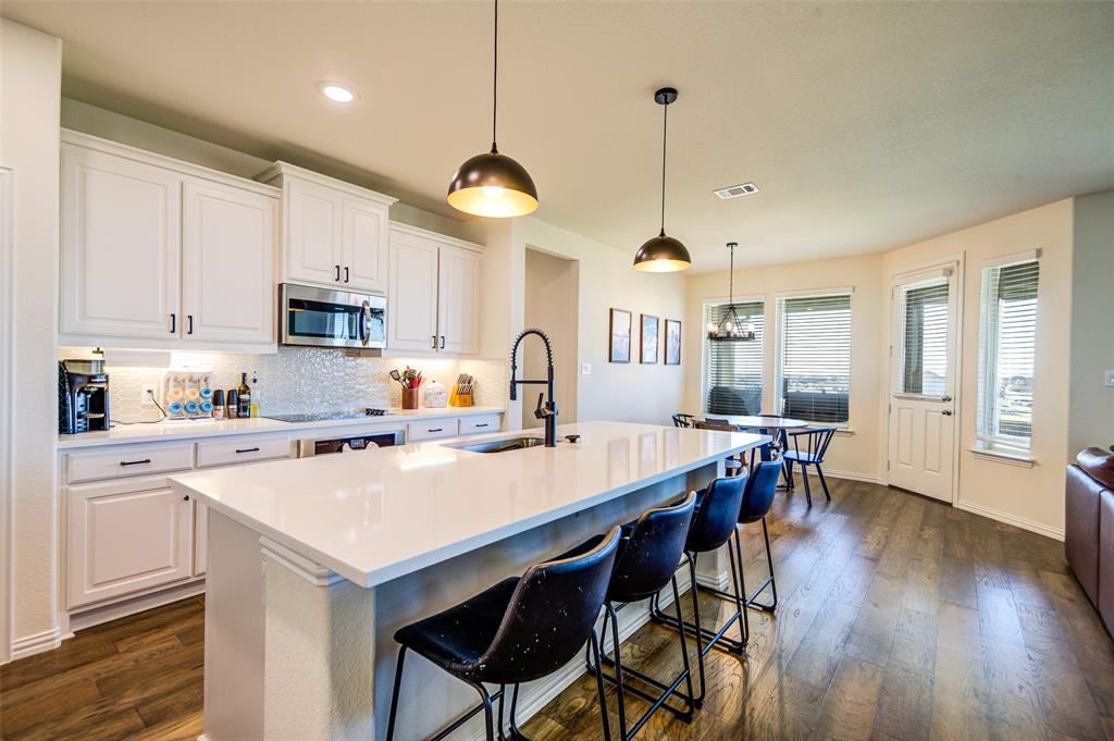 131 Clear Crk Lane Rhome, TX 76078 - Photo 2 of 29 Kitchen featuring a breakfast bar, white cabinets, an island with sink, tasteful backsplash, and dark wood-type flooring