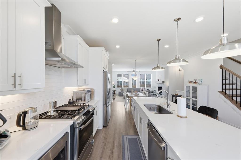 3193 Bartee Walk Suwanee, GA 30024 - Photo 11 of 27 a kitchen with kitchen island a stove a sink a center island and wooden floor