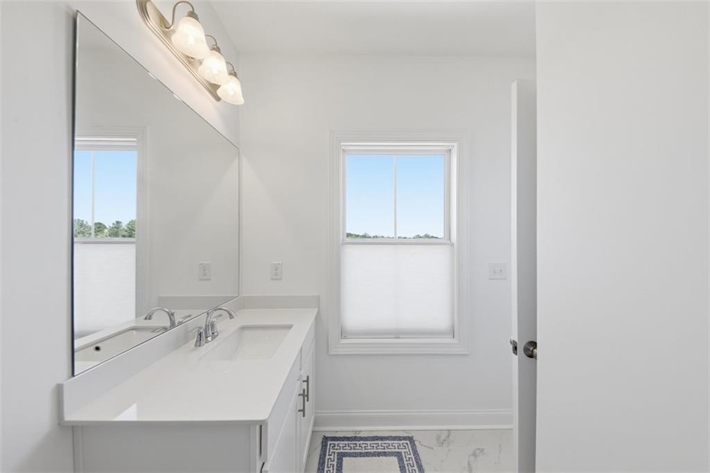 3193 Bartee Walk Suwanee, GA 30024 - Photo 20 of 27 a bathroom with a sink a mirror and a vanity