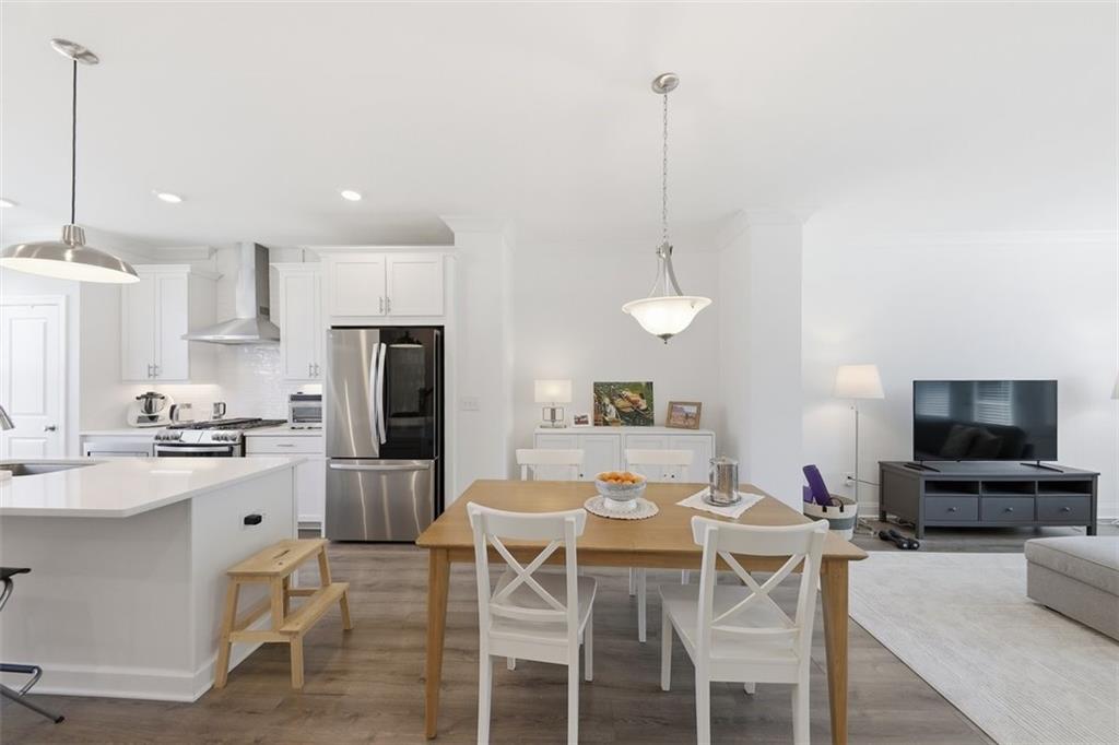 3193 Bartee Walk Suwanee, GA 30024 - Photo 9 of 27 a kitchen with stainless steel appliances kitchen island granite countertop a dining table chairs and a refrigerator