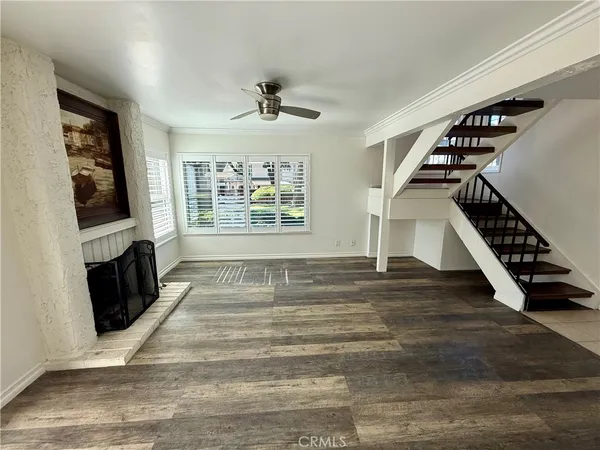 a view of an empty room with wooden floor fireplace and a window