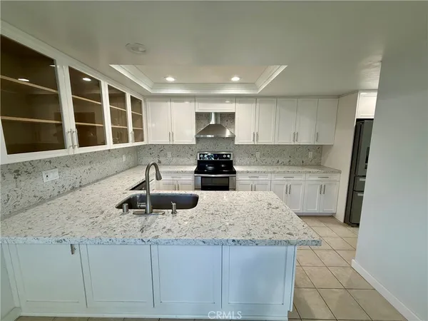 a kitchen with granite countertop a stove a sink and a refrigerator