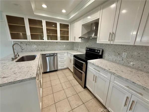 a kitchen with granite countertop a sink a stove and cabinets