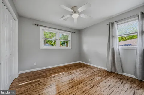 a view of empty room with wooden floor and fan