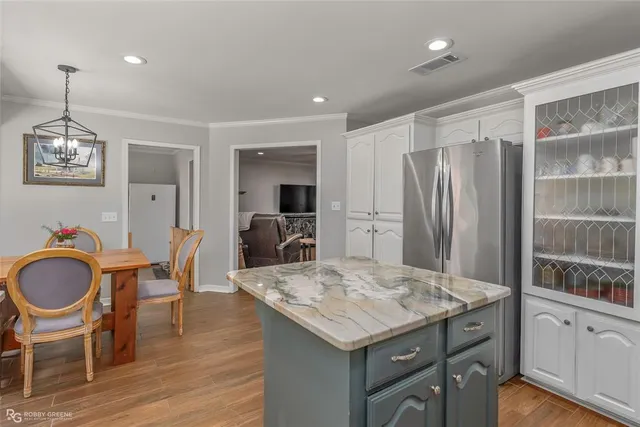 a kitchen with granite countertop a table chairs stove refrigerator and cabinets