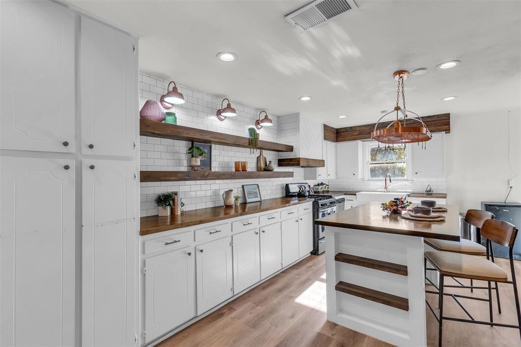 603 Lilly Street Cleburne, TX 76033 - Photo 11 of 30 Kitchen featuring gas stove, white cabinetry, light hardwood / wood-style flooring, backsplash, and pendant lighting