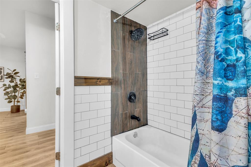 603 Lilly Street Cleburne, TX 76033 - Photo 21 of 30 Bathroom featuring shower / bathtub combination, wood-type flooring, and tile walls