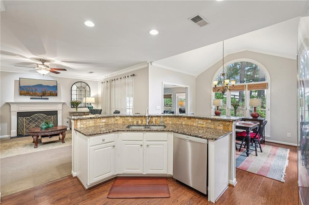 3820 Ridge Point Drive Suwanee, GA 30024 - Photo 11 of 41 a open kitchen with granite countertop a stove a sink a dining table and chairs with wooden floor