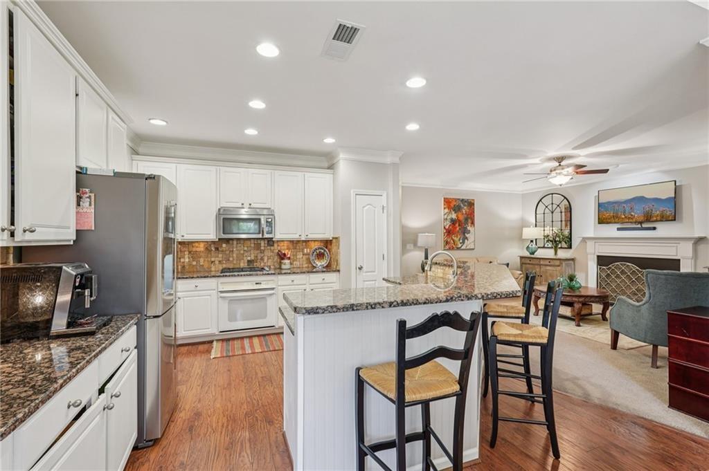 3820 Ridge Point Drive Suwanee, GA 30024 - Photo 13 of 41 a kitchen with stainless steel appliances granite countertop a table chairs sink refrigerator and cabinets
