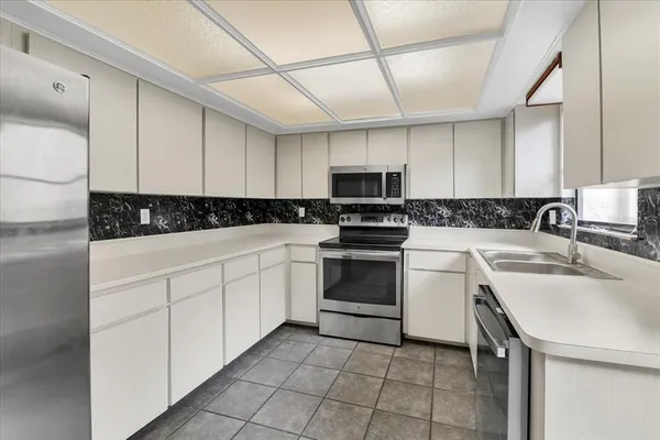 a kitchen with white cabinets and refrigerator
