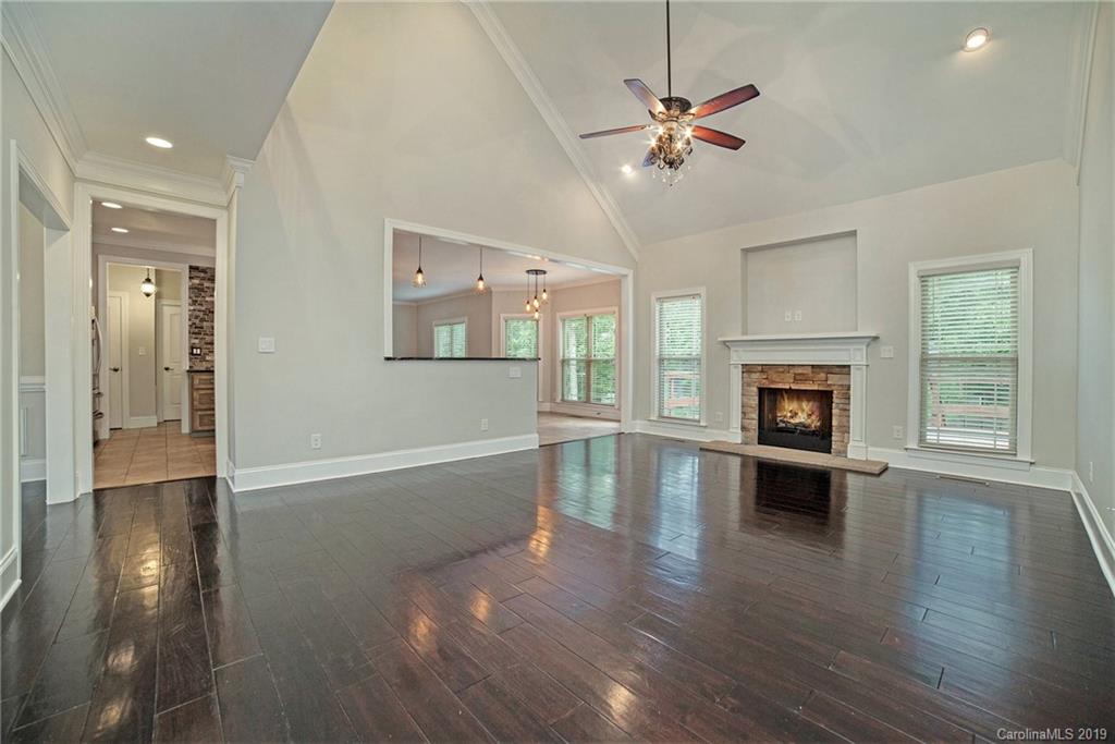 5415 Unionville Road Monroe, NC 28110 - Photo 2 of 40 an empty room with wooden floor a ceiling fan a fireplace and windows