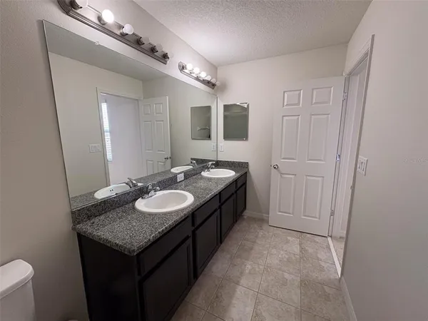 a spacious bathroom with a granite countertop sink a mirror and a vanity