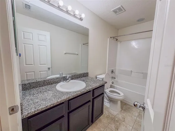 a bathroom with a granite countertop sink mirror vanity and toilet