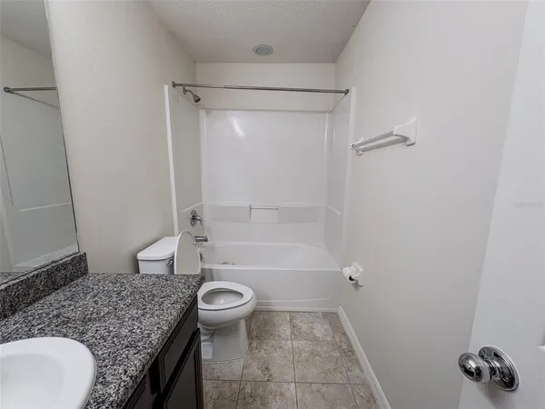 a bathroom with a granite countertop sink a toilet and shower