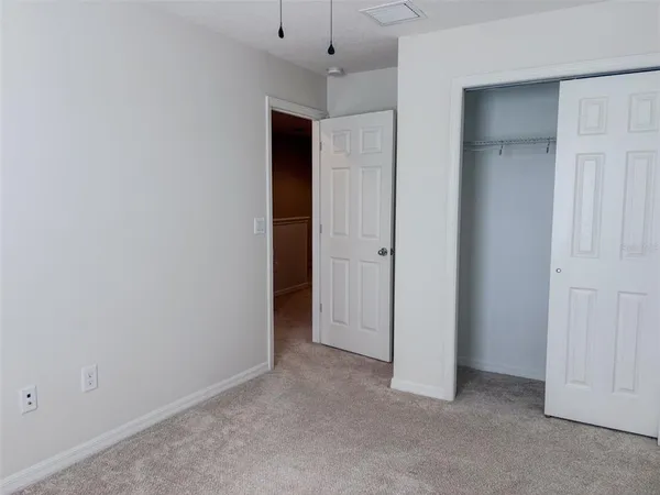 an empty room with closet and a chandelier fan