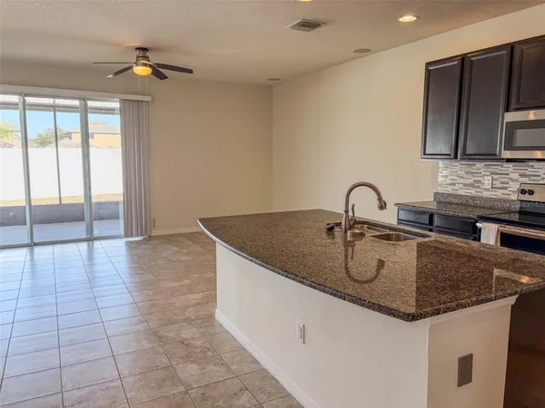 a kitchen with granite countertop a sink a counter top space and cabinets