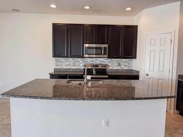 a kitchen with kitchen island granite counter tops and a stove