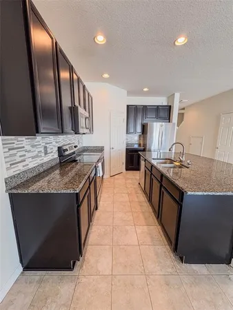 a large kitchen with granite countertop a sink and a stove