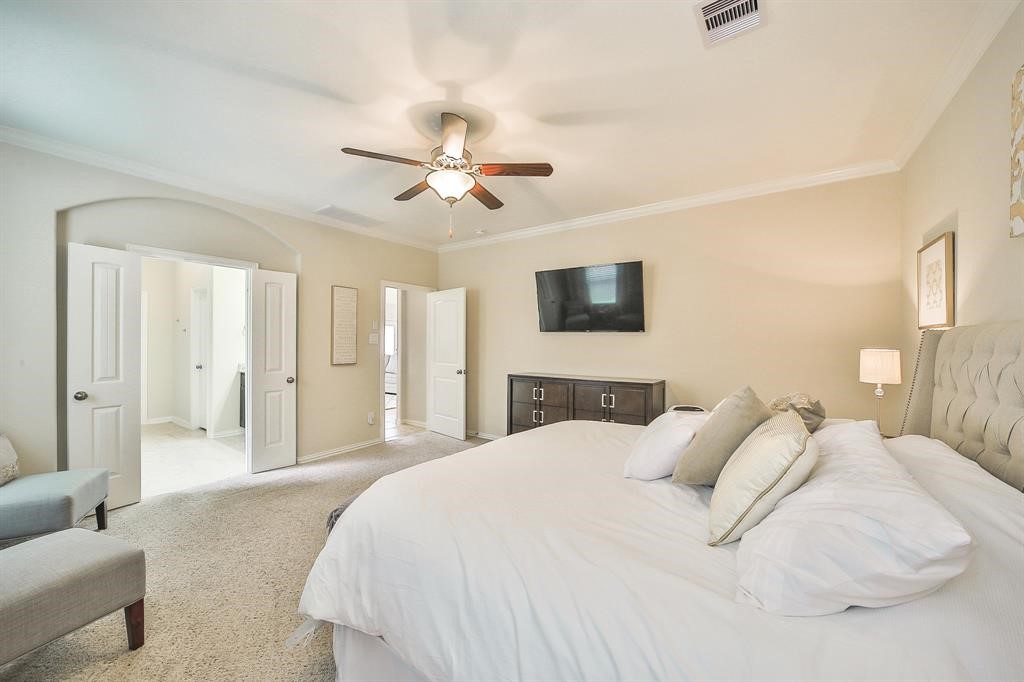 8510 Brinklow Point Drive Cypress, TX 77433 - Photo 16 of 46 a spacious bedroom with a bed a couch and a chandelier