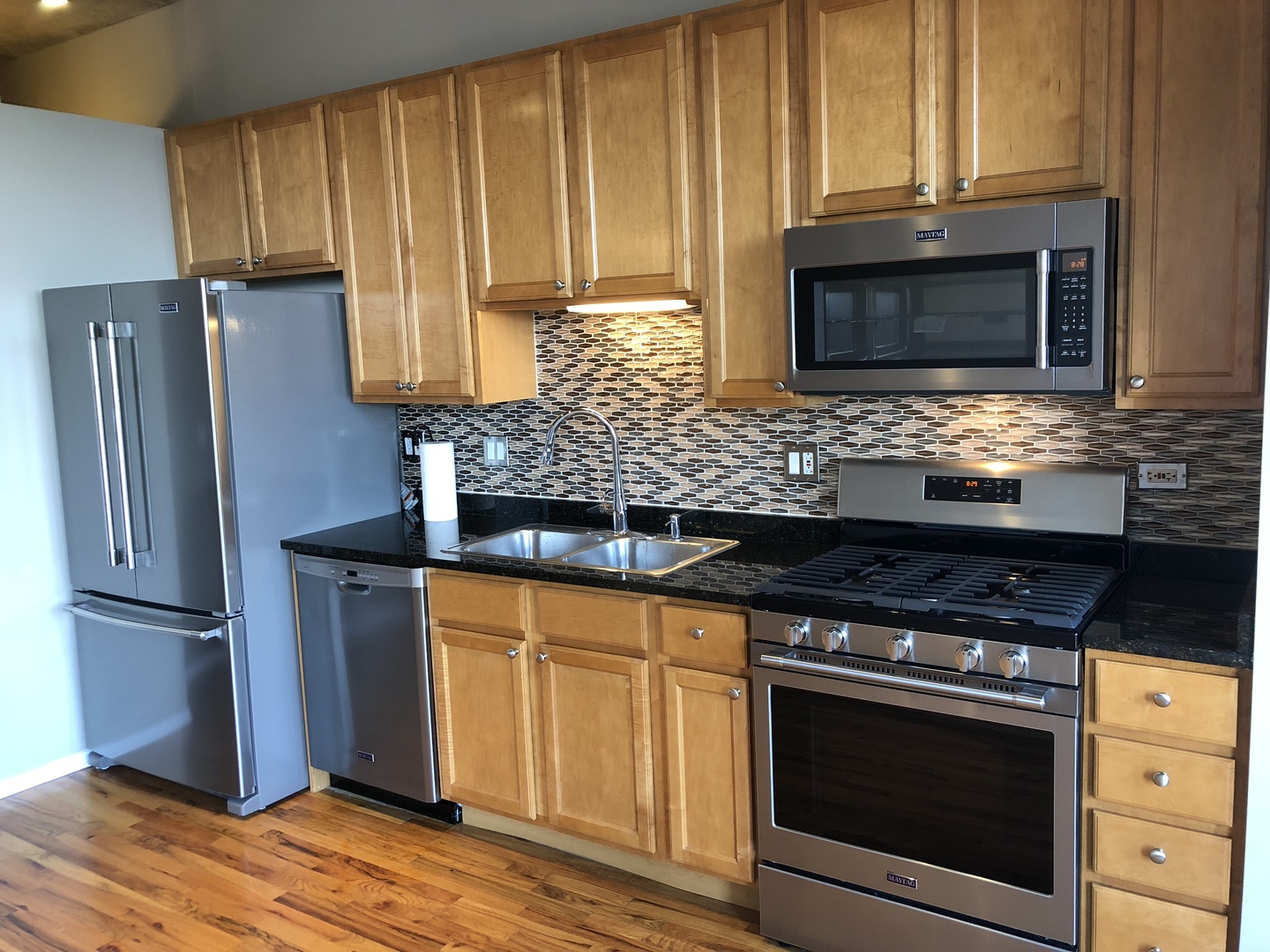 6 South Laflin Street, Unit 604 Chicago, IL 60607 - Photo 7 of 17 a kitchen with granite countertop wooden cabinets and a stove top oven