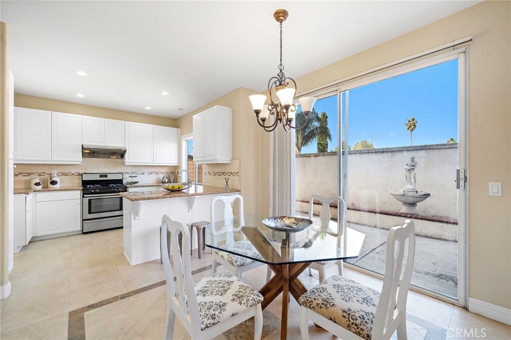8971 Poinsettia Lane Garden Grove, CA 92841 - Photo 12 of 34 a kitchen with stainless steel appliances kitchen island granite countertop a dining table chairs and white cabinets