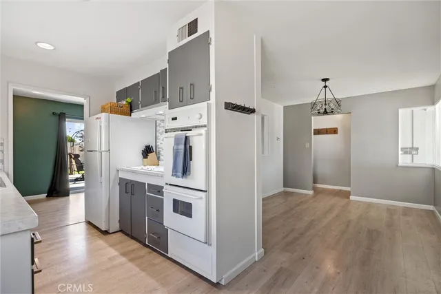 a view of a hallway with wooden floor and a kitchen