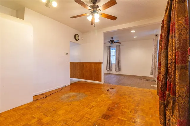 a view of a livingroom with a chandelier fan and a kitchen view