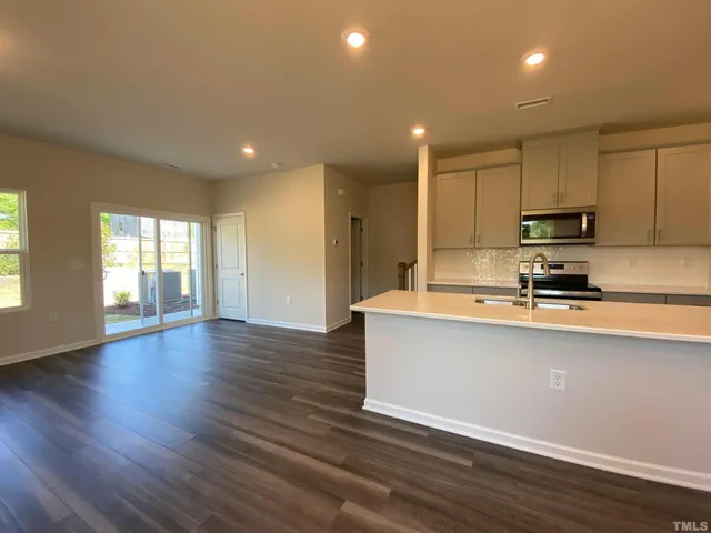 a large kitchen with stainless steel appliances granite countertop a large counter top a stove and a wooden floors