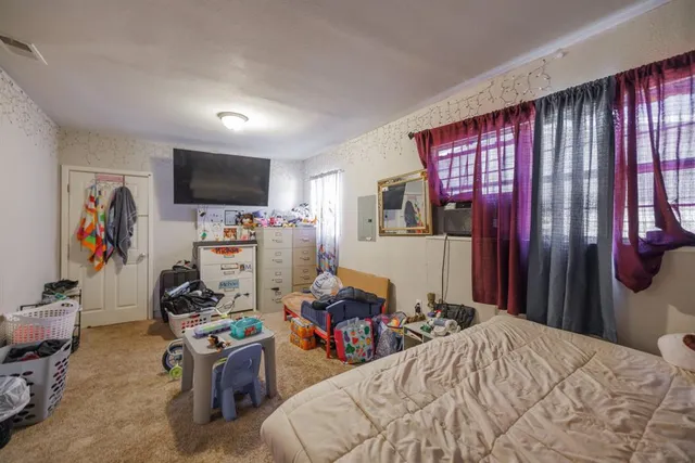 a bedroom with a bed a flat screen tv and dresser