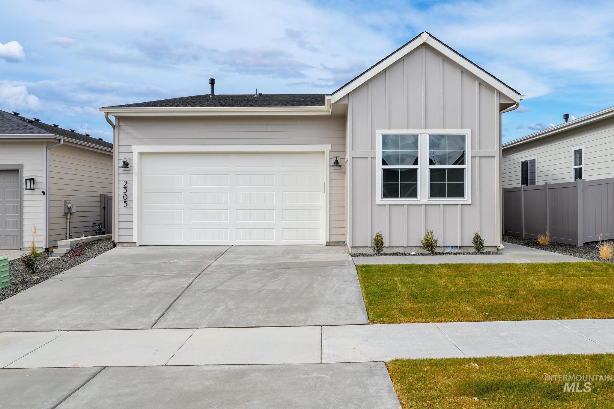 Ranch-style house featuring board and batten siding, an attached garage, and driveway