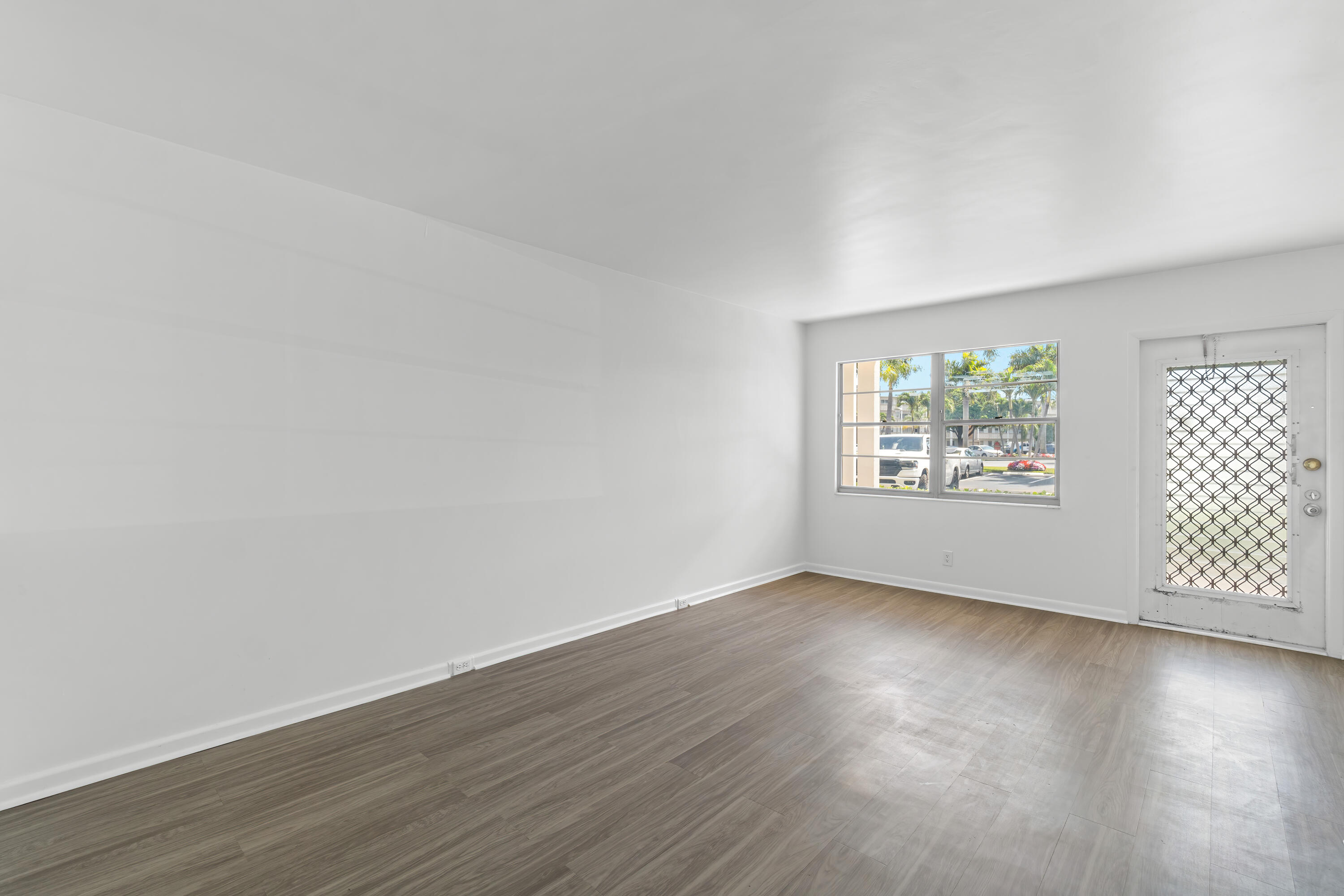 1007 Rexford Drive, Unit 1007 Boca Raton, FL 33434 - Photo 3 of 21 an empty room with wooden floor and windows