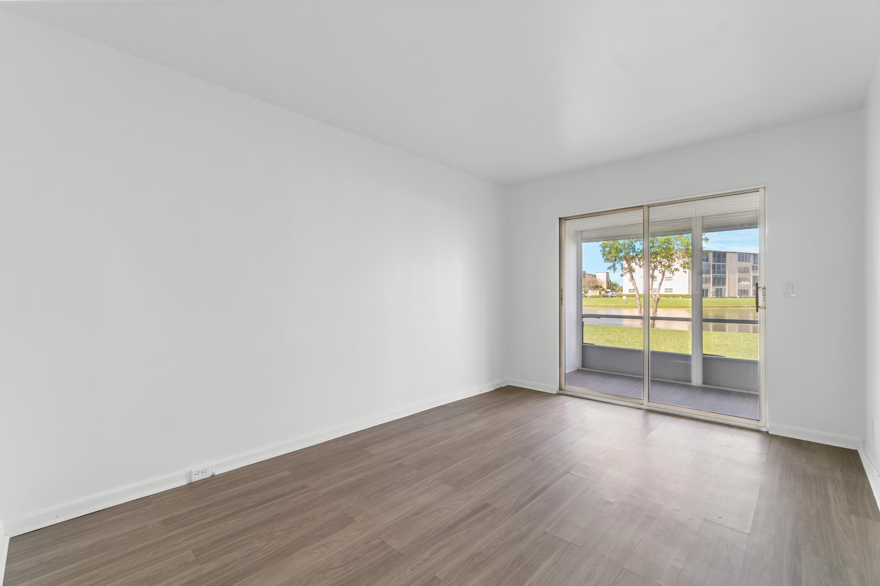1007 Rexford Drive, Unit 1007 Boca Raton, FL 33434 - Photo 8 of 21 an empty room with wooden floor and windows