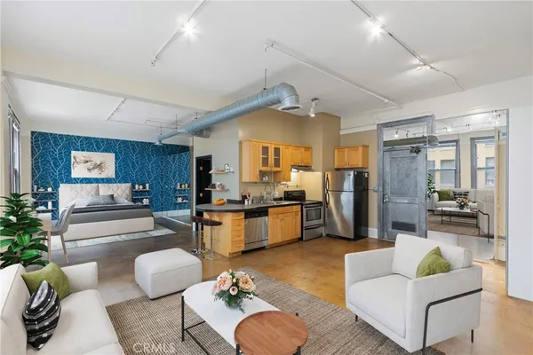 a living room with furniture kitchen view and a wooden floor