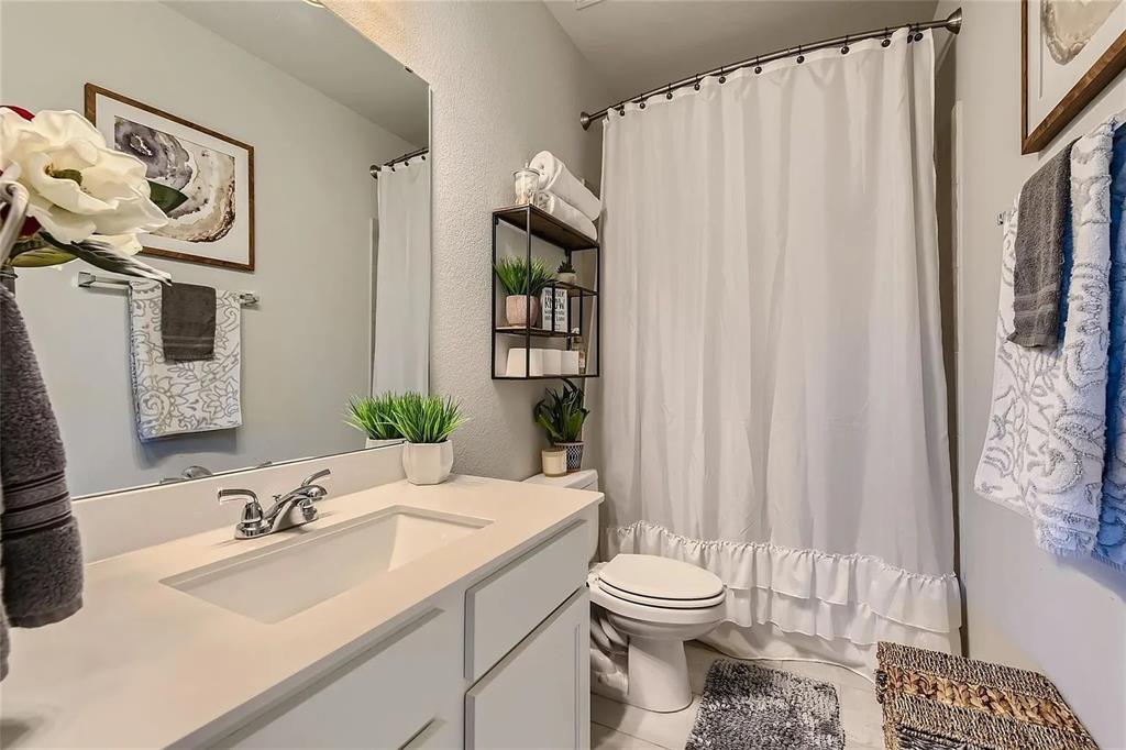 242 Freeman Loop Liberty Hill, TX 78642 - Photo 18 of 27 a bathroom with a sink a toilet and shower curtain