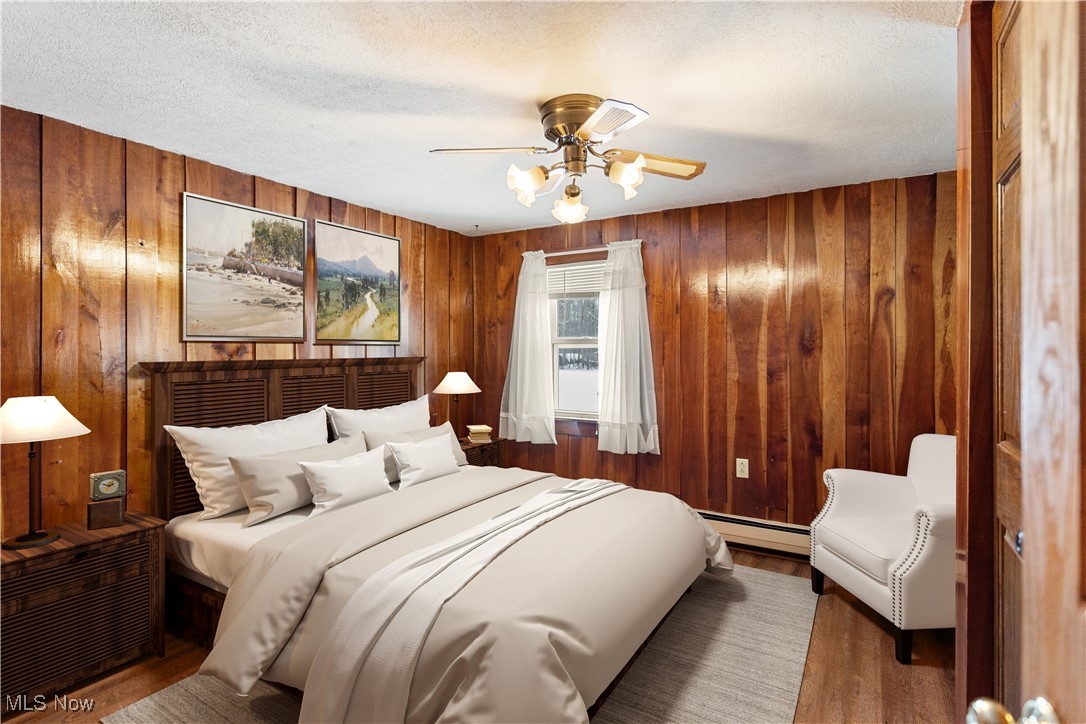 5070 Russell Road Andover, OH 44003 - Photo 9 of 25 Bedroom featuring a textured ceiling, a baseboard radiator, ceiling fan, and wood walls