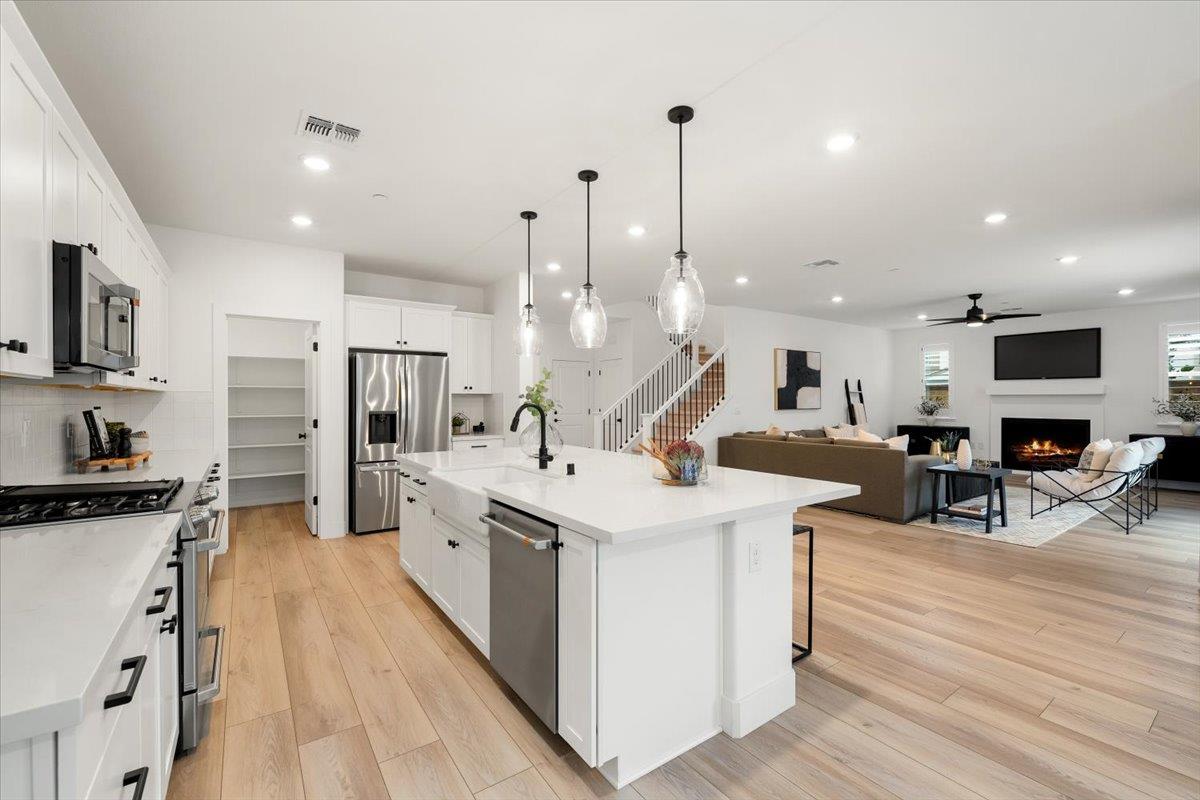 280 Vectra Court Roseville, CA 95747 - Photo 6 of 84 a large white kitchen with stainless steel appliances kitchen island a stove a refrigerator a oven a dining table and chairs with wooden floor