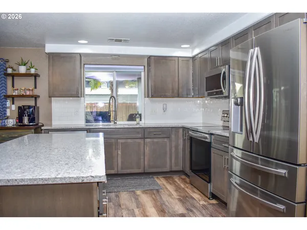 a kitchen with kitchen island a counter top space cabinets stainless steel appliances and a window