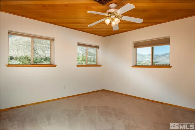 an empty room with chandelier fan and windows