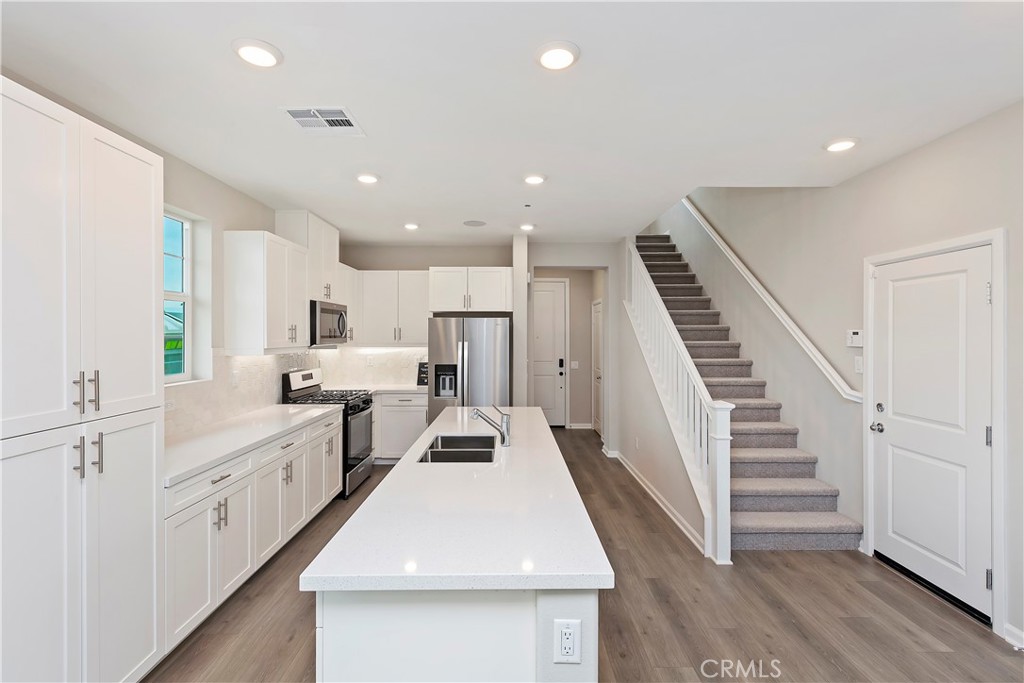 7179 Rindle Lane Riverside, CA 92503 - Photo 5 of 21 a large white kitchen with white cabinets and wooden floor
