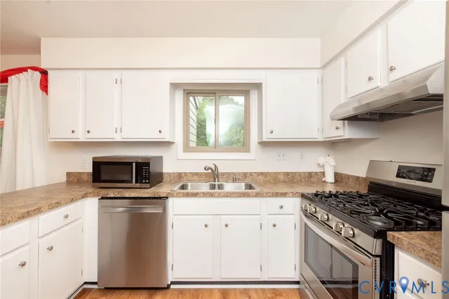 a kitchen with granite countertop a stove sink and cabinets
