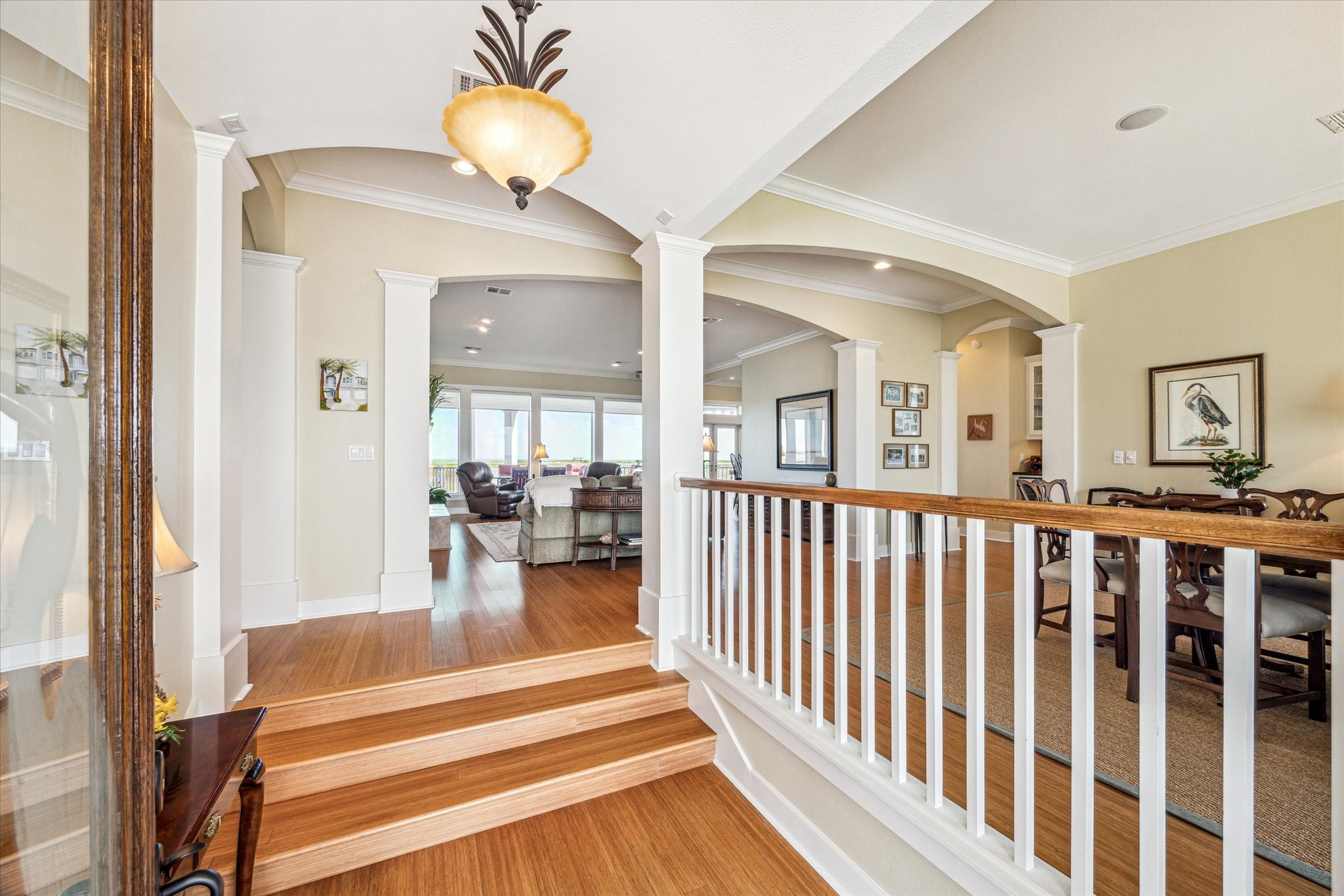 1 Shell Key Hitchcock, TX 77563 - Photo 8 of 50 Upon entry, you're welcomed by rich bamboo flooring and staircase that leads into an open-concept layout. Elegant wood-columned archways define the space, creating a seamless flow from the foyer to the living and dining areas and beyond
