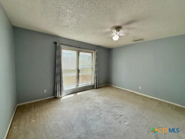an empty room with windows and ceiling fan