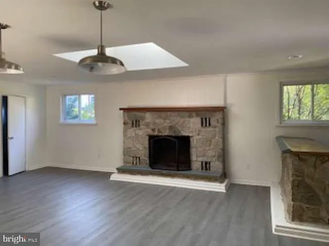 a view of an empty room with wooden floor fireplace and a window
