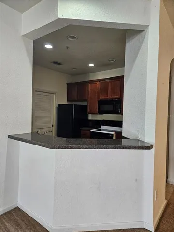 a view of kitchen with stainless steel appliances wooden cabinets and a counter top space