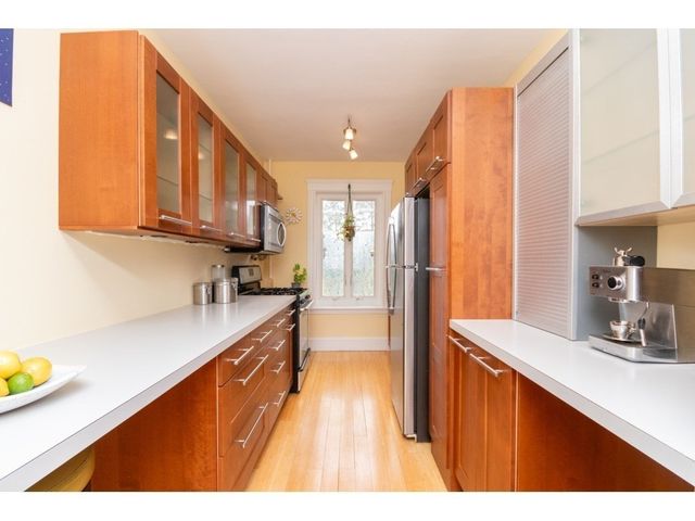 a kitchen with stainless steel appliances granite countertop a refrigerator a sink dishwasher and wooden cabinets with wooden floor