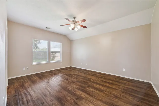 a view of an empty room with window and wooden floor